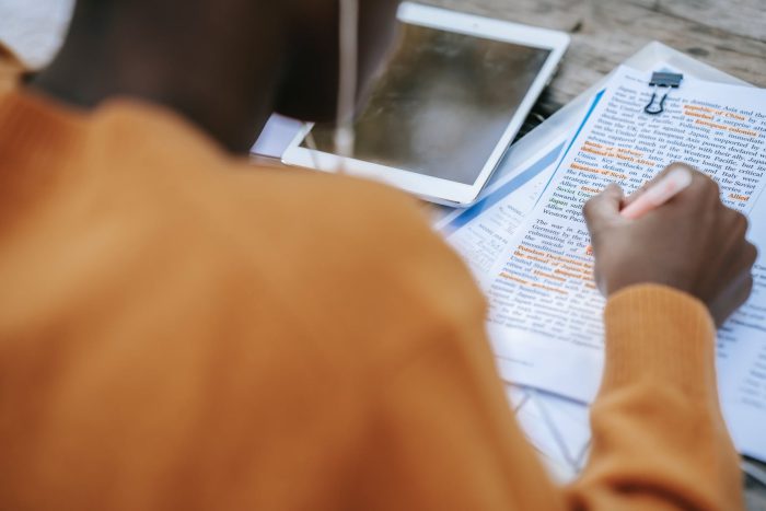 black person in earphones highlighting words in text on paper